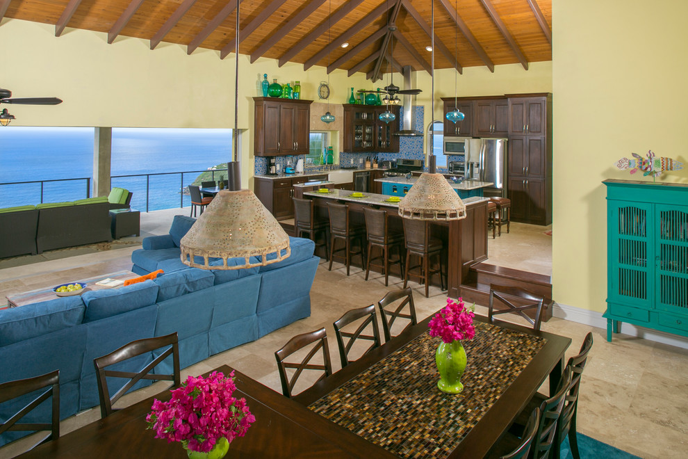 Expansive beach style open plan dining in Other with yellow walls, travertine floors, a standard fireplace, a stone fireplace surround and beige floor.