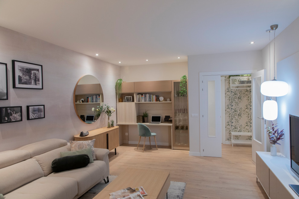 Foto di un soggiorno scandinavo di medie dimensioni e chiuso con libreria, pareti beige, pavimento in laminato, TV autoportante, pavimento marrone e carta da parati