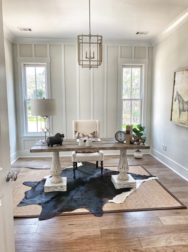Country home office in Atlanta with white walls, medium hardwood floors, a freestanding desk and brown floor.