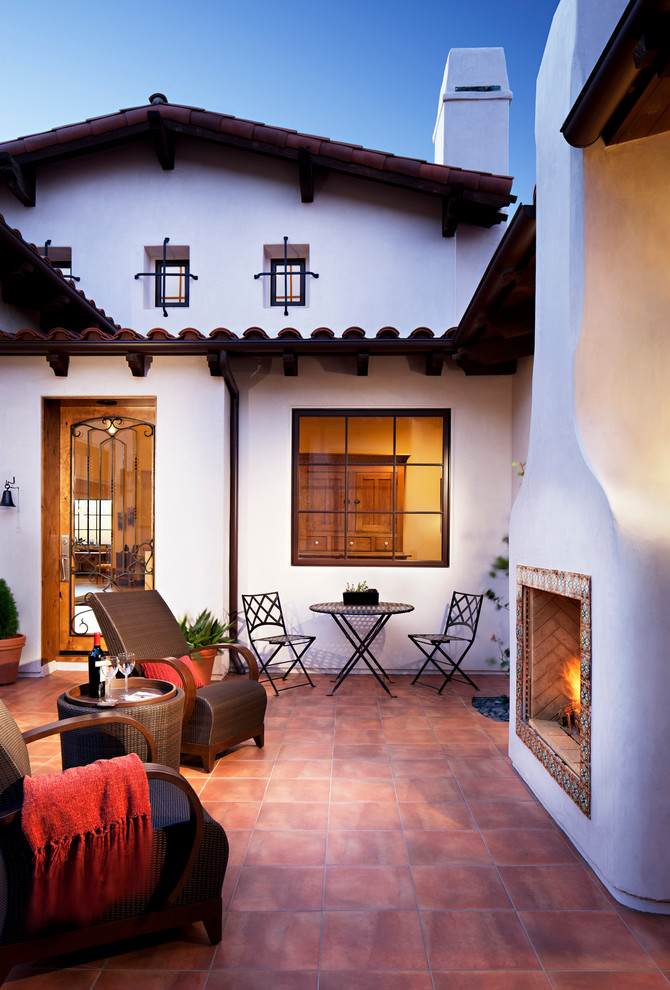Large mediterranean courtyard patio in San Diego with a fire feature, natural stone pavers and no cover.