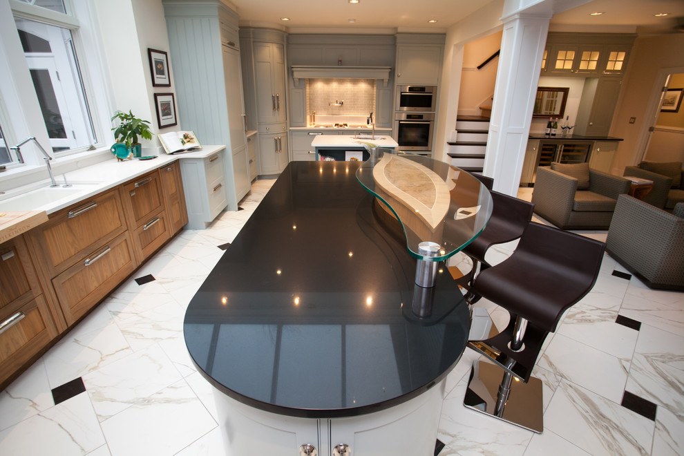 This is an example of a mid-sized contemporary l-shaped eat-in kitchen in DC Metro with an undermount sink, recessed-panel cabinets, blue cabinets, soapstone benchtops, grey splashback, glass tile splashback, stainless steel appliances, marble floors, multiple islands and white floor.