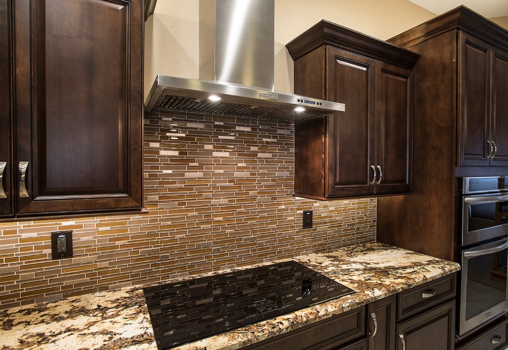 Example of a mid-sized transitional l-shaped ceramic tile open concept kitchen design in Phoenix with an undermount sink, raised-panel cabinets, dark wood cabinets, granite countertops, brown backsplash, glass tile backsplash, stainless steel appliances and an island