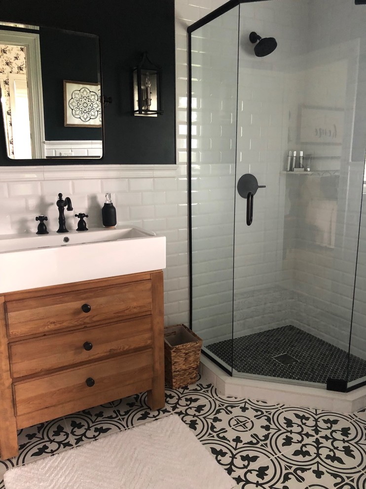 Design ideas for a small country bathroom in Chicago with light wood cabinets, a corner shower, a one-piece toilet, white tile, ceramic tile, black walls, ceramic floors, a trough sink, black floor, a hinged shower door and flat-panel cabinets.