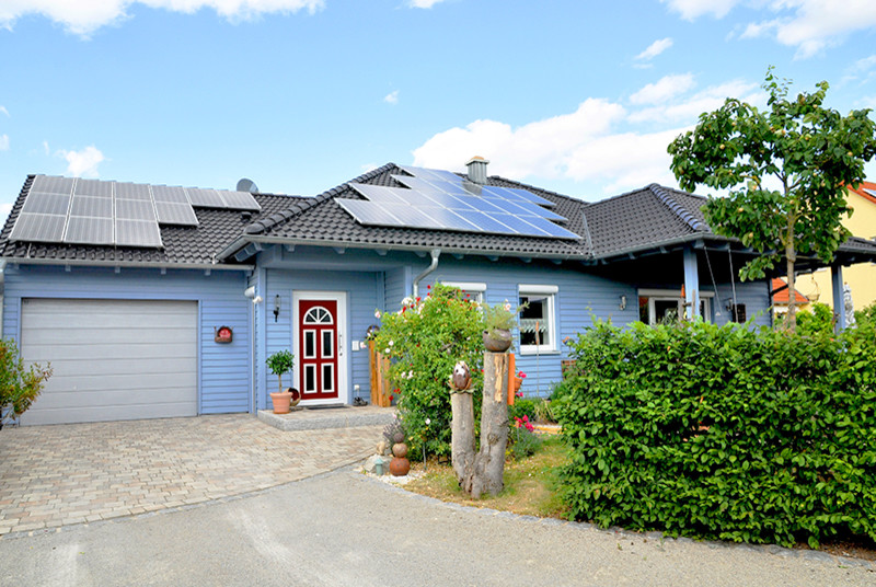 Photo of a scandinavian one-storey blue house exterior in Nuremberg with wood siding, a hip roof and a tile roof.