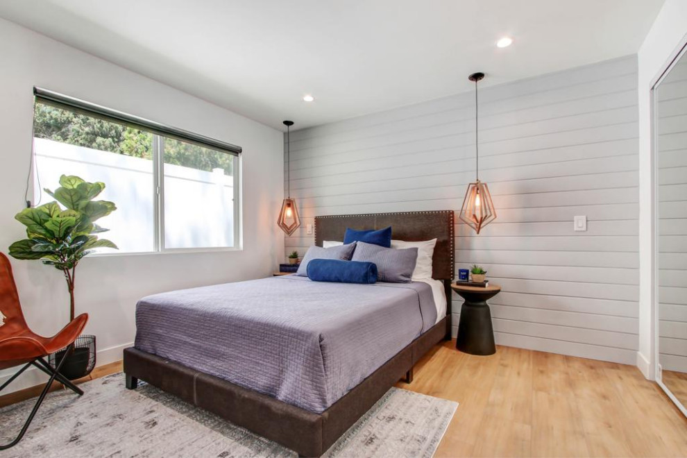 Inspiration for a mid-sized transitional master bedroom in Los Angeles with white walls, vinyl floors, planked wall panelling, brown floor and wallpaper.