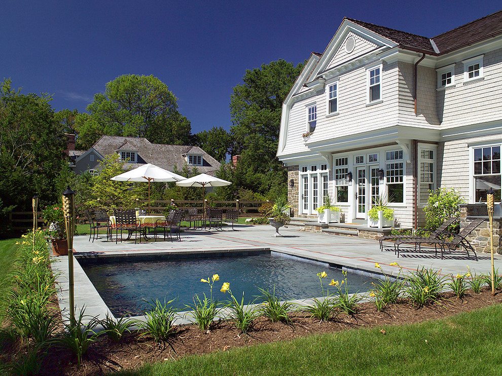 Photo of a mid-sized traditional backyard rectangular pool in Philadelphia with natural stone pavers.
