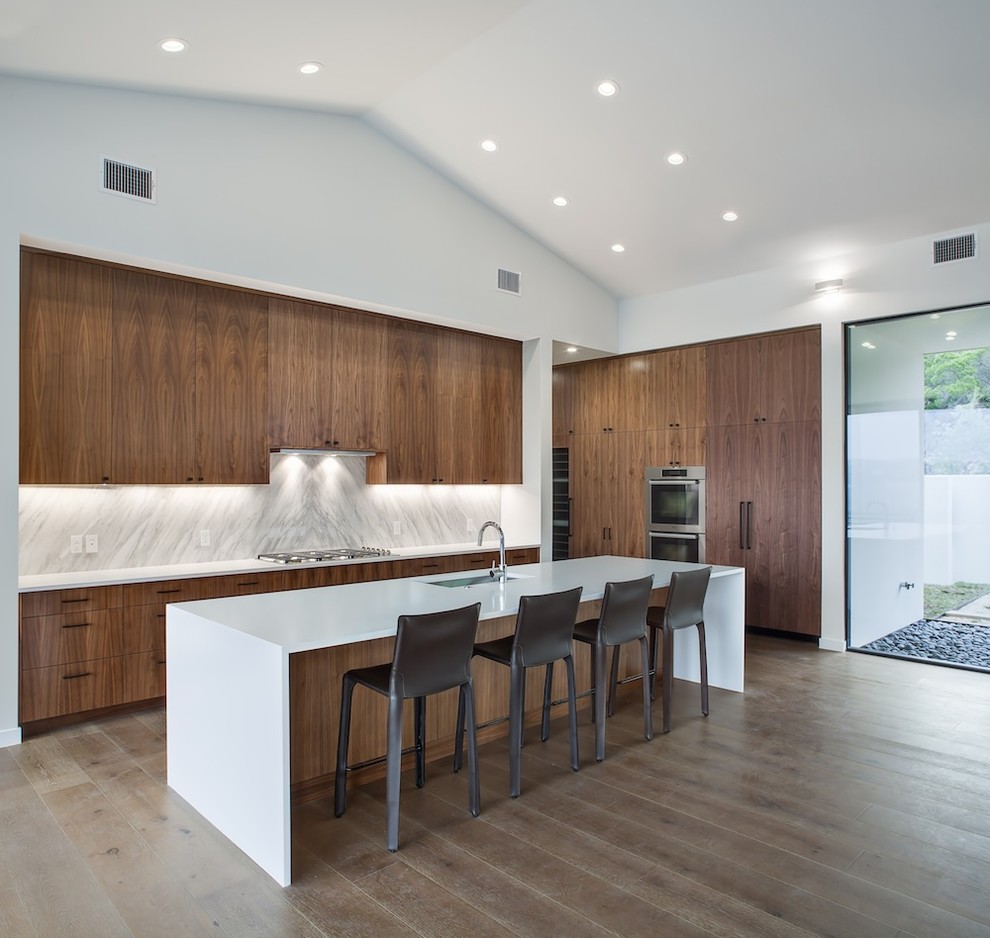 Inspiration for a contemporary l-shaped open plan kitchen in Austin with an undermount sink, flat-panel cabinets, dark wood cabinets, white splashback, stone slab splashback, medium hardwood floors and with island.
