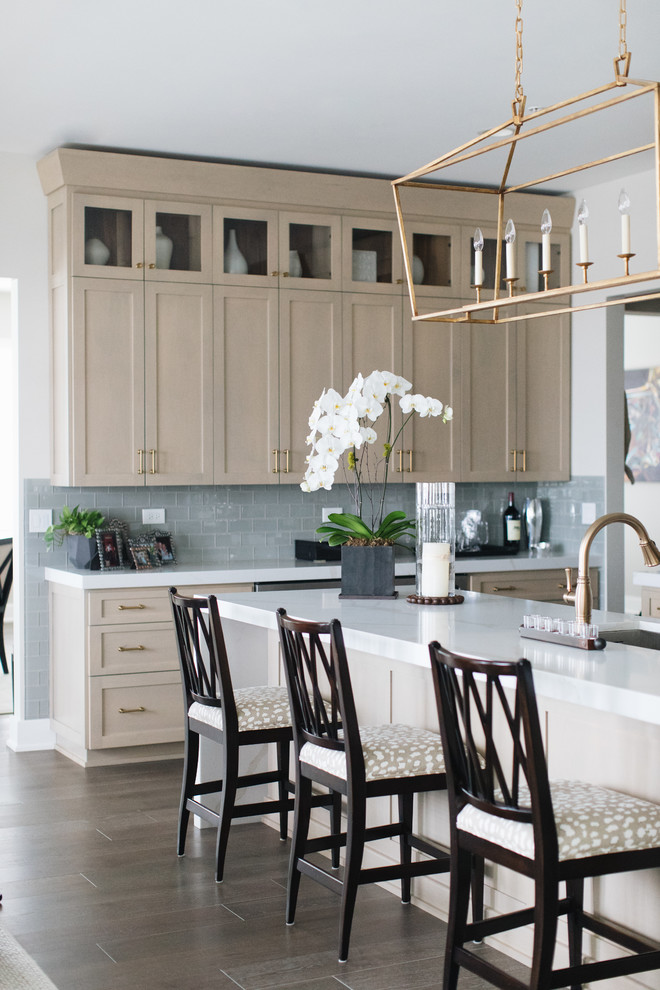 Inspiration for a large transitional u-shaped medium tone wood floor and brown floor kitchen remodel in Chicago with an undermount sink, shaker cabinets, beige cabinets, quartz countertops, glass tile backsplash, stainless steel appliances, an island and white countertops