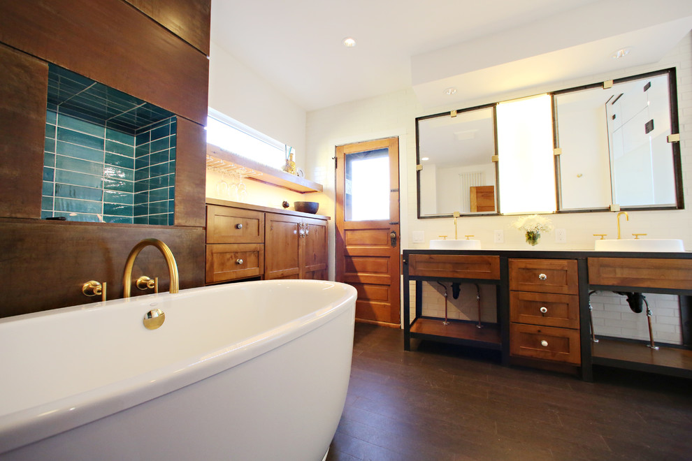 Large industrial master bathroom in Minneapolis with a drop-in sink, recessed-panel cabinets, medium wood cabinets, concrete benchtops, a freestanding tub, an alcove shower, a one-piece toilet, white tile, porcelain tile, white walls and cork floors.