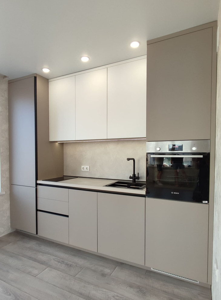 This is an example of a small contemporary single-wall separate kitchen in Novosibirsk with a drop-in sink, flat-panel cabinets, white cabinets, wood benchtops, beige splashback, timber splashback, black appliances, laminate floors, no island, grey floor and beige benchtop.