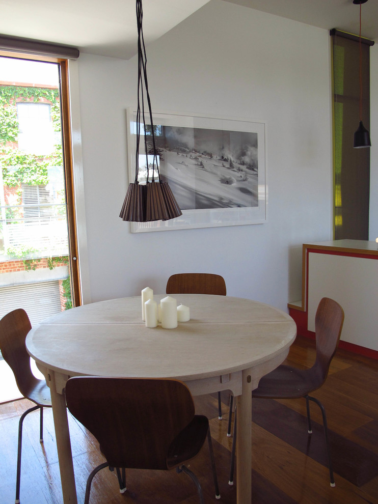 Photo of a small contemporary open plan dining in Melbourne with white walls, light hardwood floors, a standard fireplace, a metal fireplace surround and orange floor.