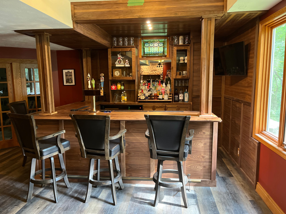This is an example of an expansive contemporary l-shaped home bar in Omaha with no sink, shaker cabinets, dark wood cabinets, wood benchtops, brown splashback, timber splashback, laminate floors, brown floor and brown benchtop.