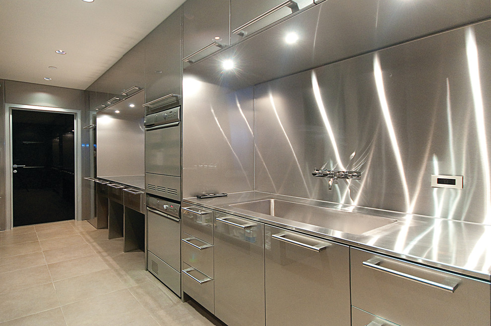 Photo of an expansive u-shaped dedicated laundry room in Vancouver with an integrated sink, flat-panel cabinets, stainless steel cabinets and stainless steel benchtops.