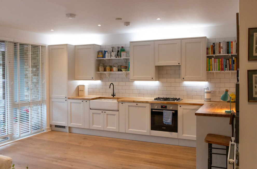 Design ideas for a medium sized modern l-shaped open plan kitchen in London with a submerged sink, shaker cabinets, white cabinets, wood worktops, porcelain splashback, integrated appliances, medium hardwood flooring, no island, brown worktops and feature lighting.