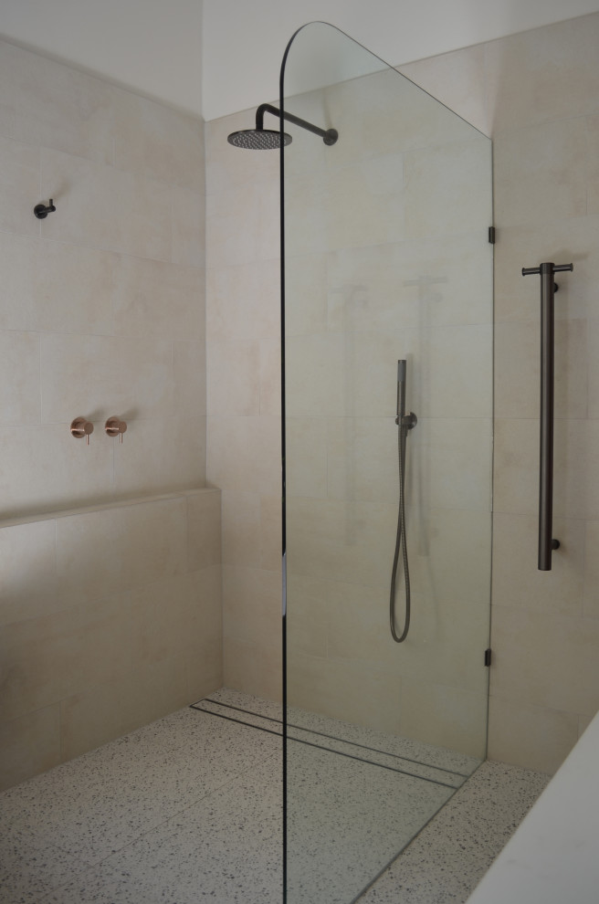 Design ideas for a mid-sized contemporary bathroom in Sydney with flat-panel cabinets, medium wood cabinets, a freestanding tub, an open shower, a one-piece toilet, beige tile, porcelain tile, beige walls, terrazzo floors, a drop-in sink, engineered quartz benchtops, grey floor, white benchtops, a single vanity and a floating vanity.