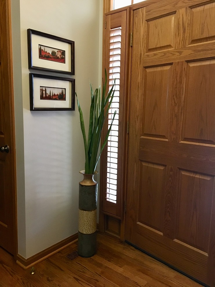 Entryway - transitional light wood floor entryway idea in Omaha with a medium wood front door