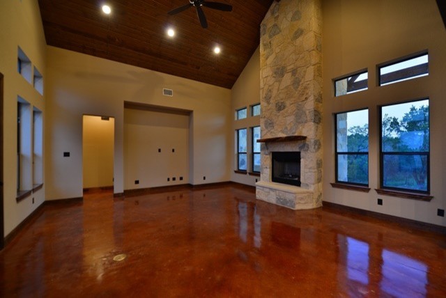 Inspiration for a mid-sized contemporary open concept family room in Austin with concrete floors, a standard fireplace, a stone fireplace surround, beige walls and no tv.