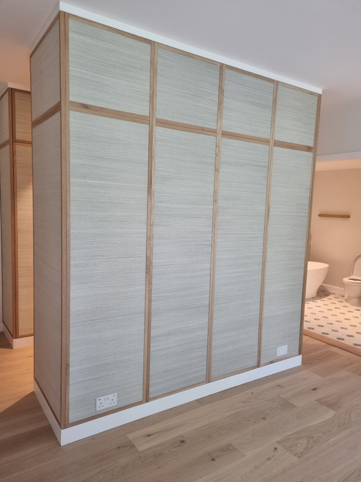 Example of a large minimalist master plywood floor bedroom design in London with beige walls