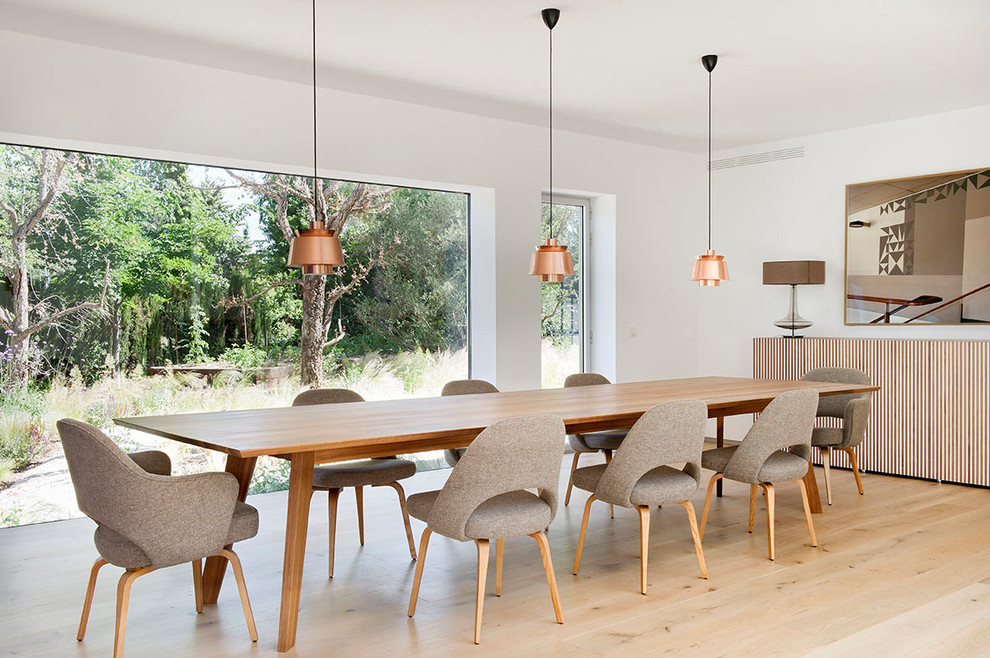 Inspiration for a contemporary dining room in Madrid with white walls, medium hardwood floors, no fireplace and beige floor.