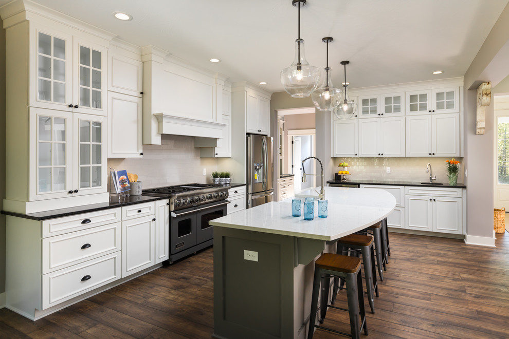 Inspiration for a large modern l-shaped eat-in kitchen in Grand Rapids with a farmhouse sink, white cabinets, quartz benchtops, grey splashback, subway tile splashback, stainless steel appliances, laminate floors and with island.