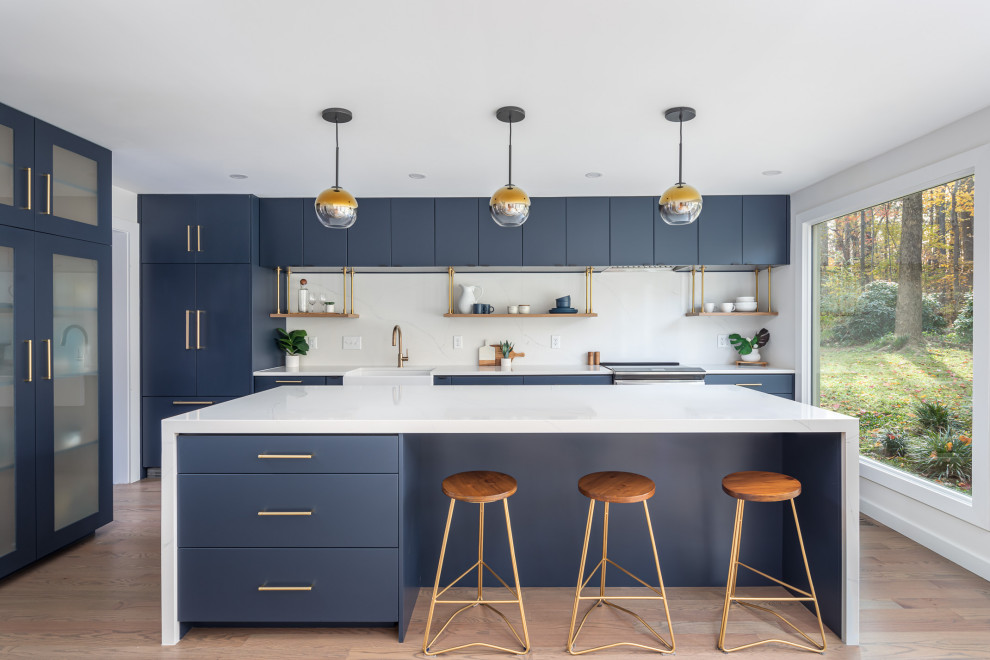 Example of a mid-sized trendy l-shaped medium tone wood floor and brown floor eat-in kitchen design in Raleigh with a farmhouse sink, flat-panel cabinets, blue cabinets, quartzite countertops, white backsplash, quartz backsplash, paneled appliances, an island and white countertops
