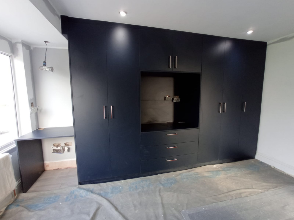 Inspiration for a traditional gender-neutral storage and wardrobe in London with flat-panel cabinets and blue cabinets.