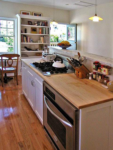 Photo of a mid-sized traditional u-shaped separate kitchen in San Francisco with a double-bowl sink, shaker cabinets, white cabinets, wood benchtops, white splashback, subway tile splashback, stainless steel appliances, light hardwood floors and with island.