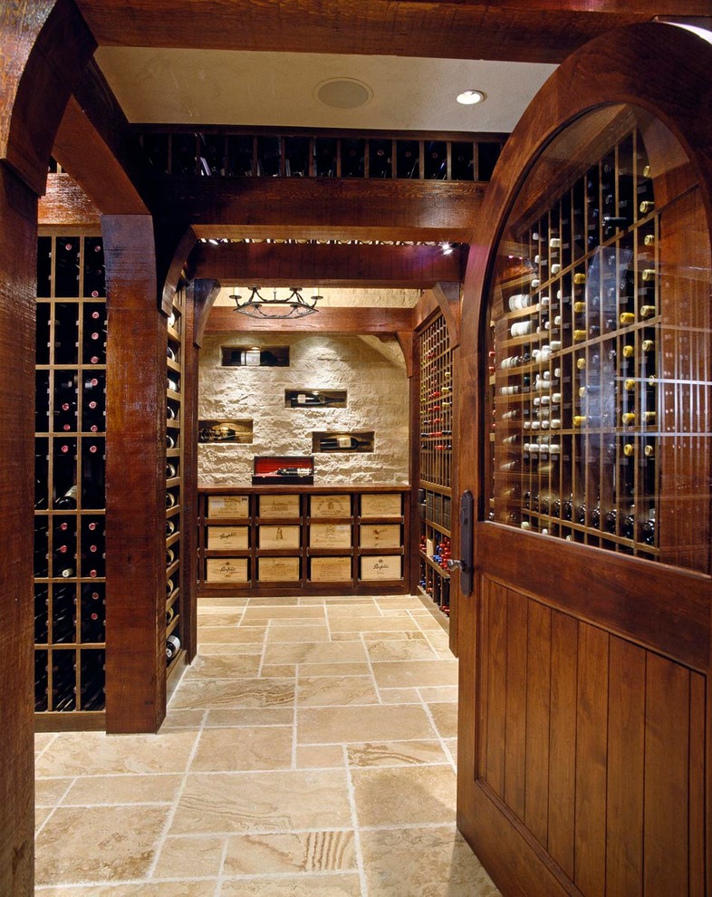 This is an example of an expansive traditional wine cellar in Boston with storage racks and travertine floors.
