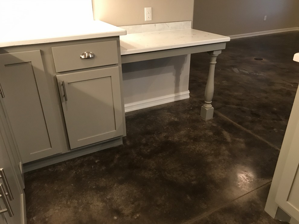 Photo of a mid-sized transitional l-shaped open plan kitchen in Oklahoma City with an undermount sink, shaker cabinets, grey cabinets, quartz benchtops, white splashback, ceramic splashback, stainless steel appliances, concrete floors, with island and grey floor.