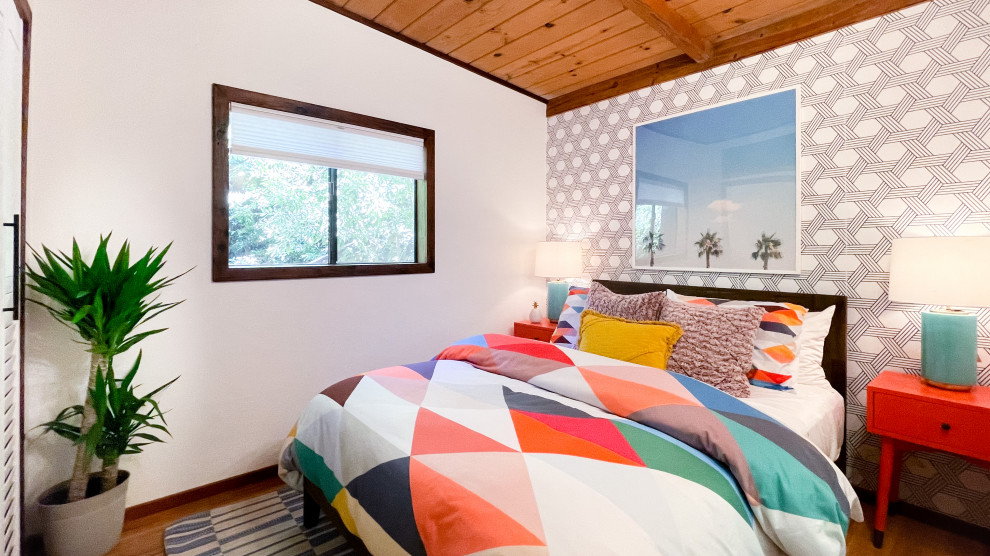 Cette photo montre une petite chambre d'amis rétro avec un mur multicolore, un sol en bois brun, aucune cheminée, un sol marron, un plafond en bois et du papier peint.