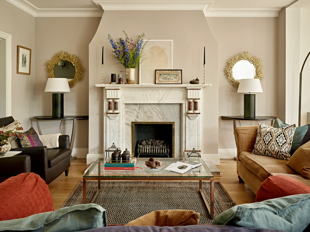 This is an example of a mid-sized transitional open concept living room in London with beige walls, a standard fireplace, a stone fireplace surround, medium hardwood floors and brown floor.