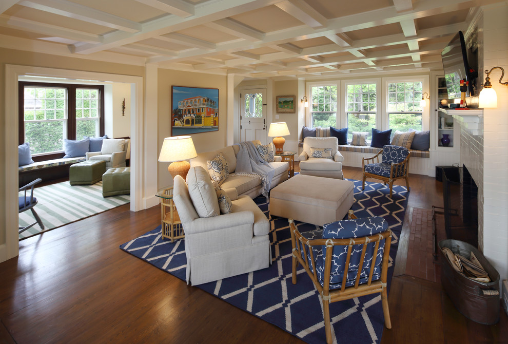Photo of a large transitional formal open concept living room in Portland Maine with medium hardwood floors, a standard fireplace, a brick fireplace surround, a wall-mounted tv and beige walls.