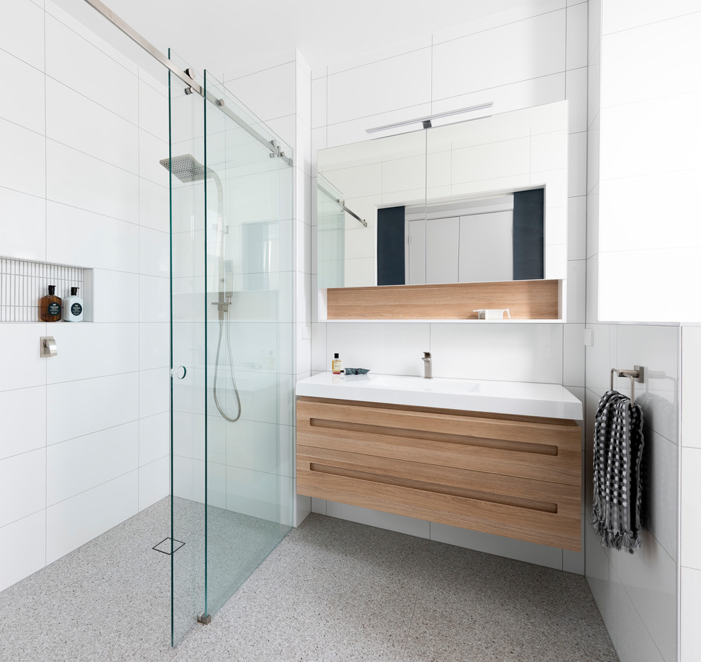 This is an example of a contemporary 3/4 bathroom in Melbourne with flat-panel cabinets, medium wood cabinets, a curbless shower, an integrated sink, grey floor, a sliding shower screen and white benchtops.