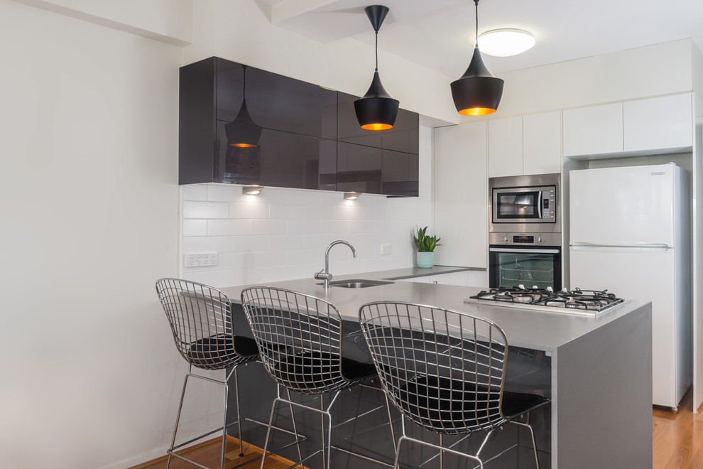 Design ideas for a small modern u-shaped eat-in kitchen in Brisbane with an undermount sink, black cabinets, white splashback, subway tile splashback, stainless steel appliances, light hardwood floors and with island.