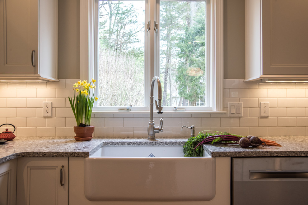 Example of a mid-sized transitional l-shaped medium tone wood floor eat-in kitchen design in Boston with a farmhouse sink, shaker cabinets, white cabinets, quartz countertops, white backsplash, subway tile backsplash, stainless steel appliances and an island