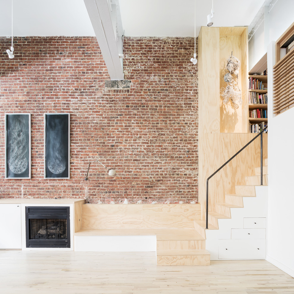 Inspiration for a large industrial open concept living room in New York with white walls, light hardwood floors, a standard fireplace, a wood fireplace surround and a concealed tv.