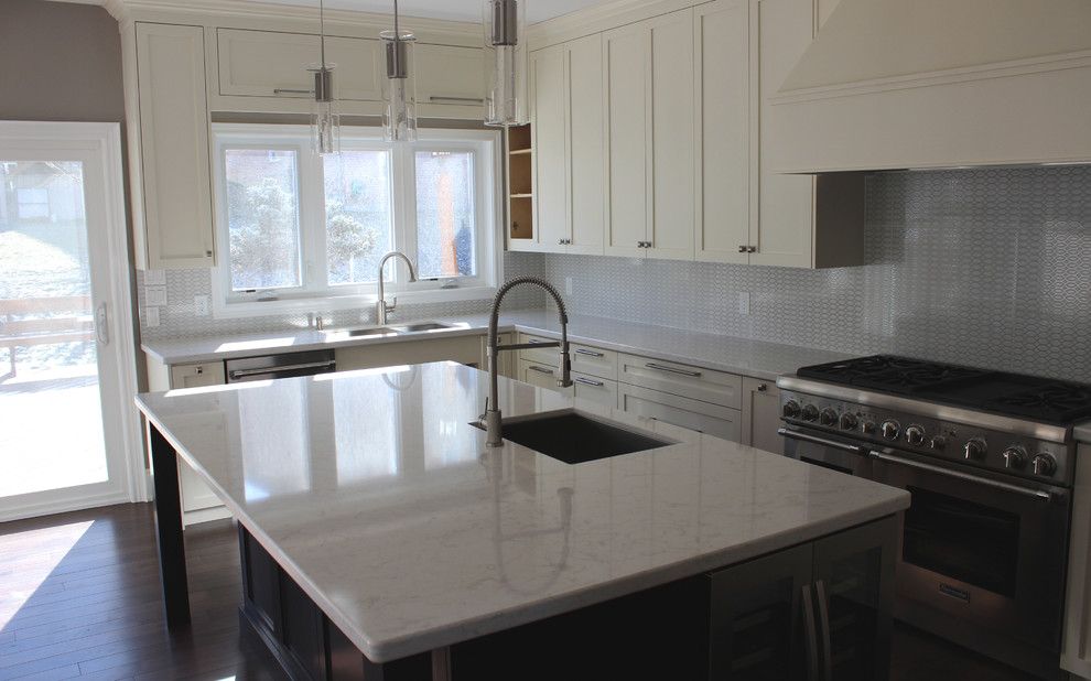 Example of a mid-sized transitional u-shaped dark wood floor open concept kitchen design in Toronto with an undermount sink, shaker cabinets, white cabinets, quartz countertops, gray backsplash, ceramic backsplash, stainless steel appliances and an island