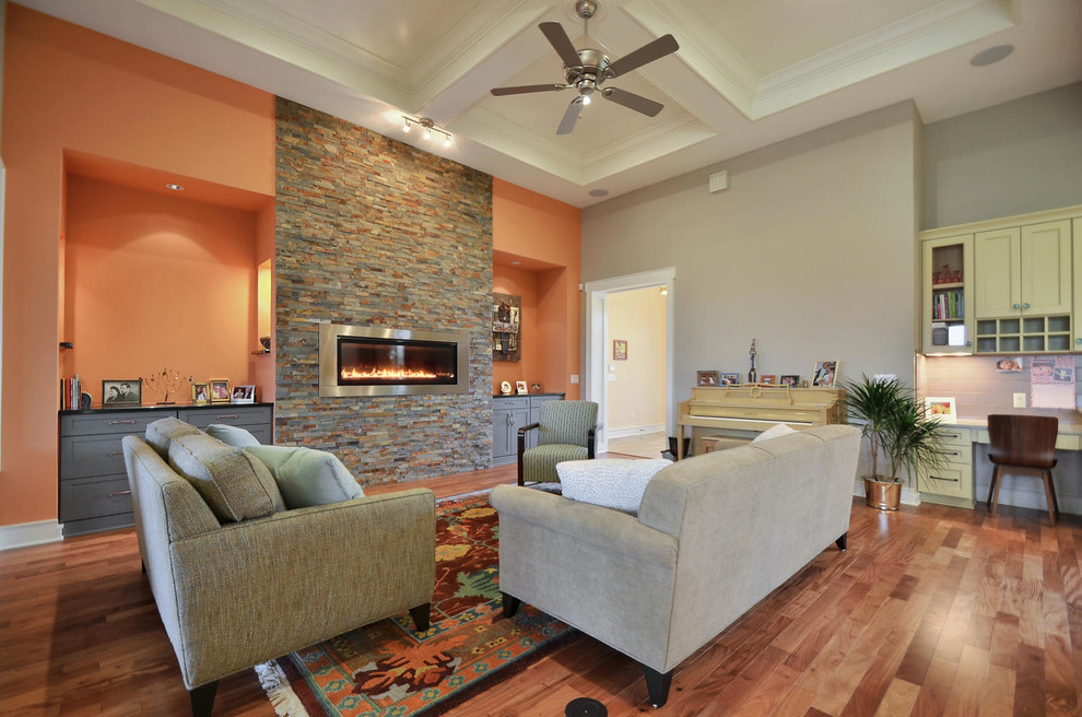 This is an example of a mid-sized transitional open concept living room in Austin with medium hardwood floors, a ribbon fireplace, a stone fireplace surround, no tv and orange walls.