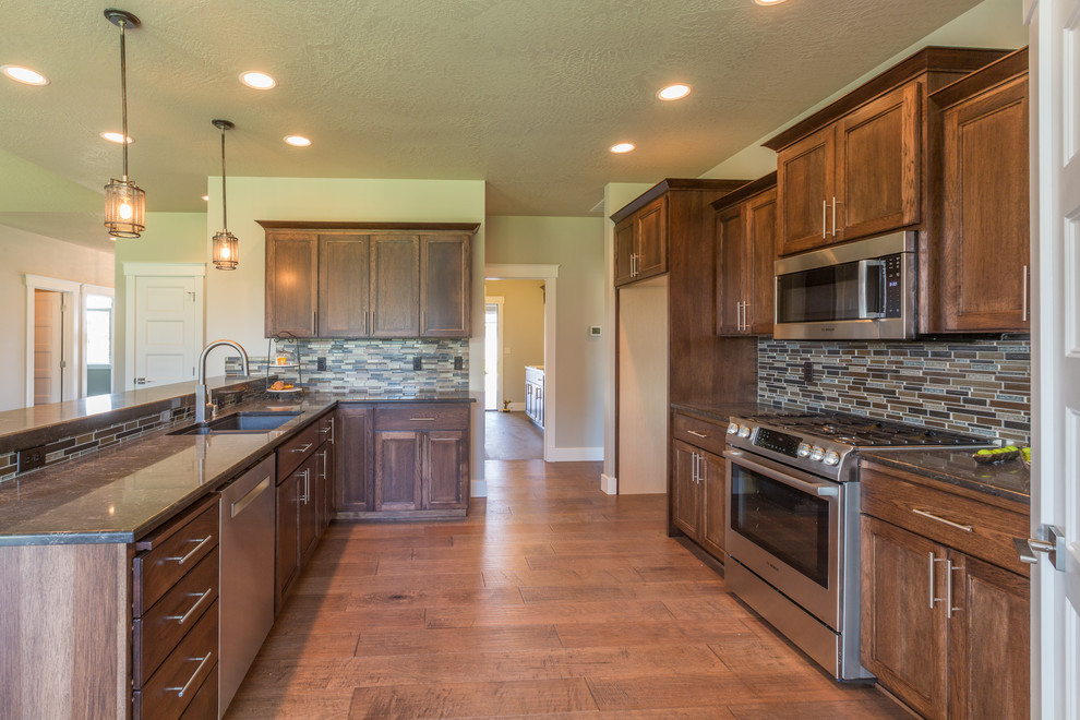 Inspiration for a mid-sized transitional l-shaped dark wood floor and brown floor open concept kitchen remodel in Seattle with a double-bowl sink, recessed-panel cabinets, dark wood cabinets, granite countertops, multicolored backsplash, matchstick tile backsplash, stainless steel appliances and an island
