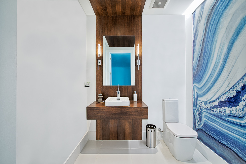 Photo of a mid-sized contemporary 3/4 bathroom in Miami with open cabinets, medium wood cabinets, a two-piece toilet, blue walls, porcelain floors, a vessel sink and wood benchtops.