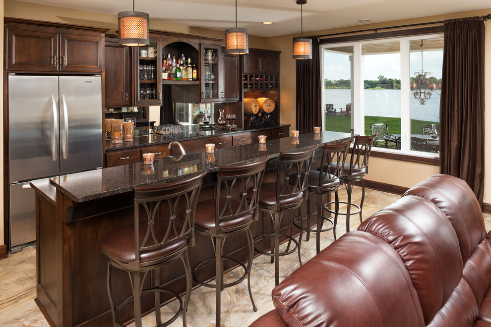 Traditional galley seated home bar in Minneapolis with recessed-panel cabinets, dark wood cabinets, mirror splashback and beige floor.