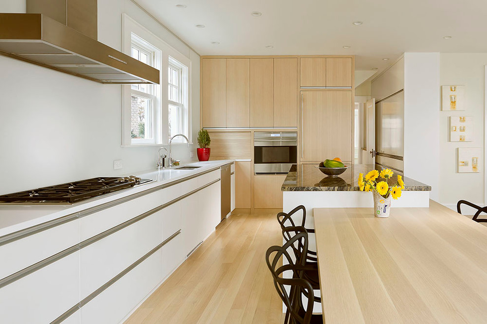 Photo of a contemporary l-shaped eat-in kitchen in Minneapolis with flat-panel cabinets, light wood cabinets and panelled appliances.