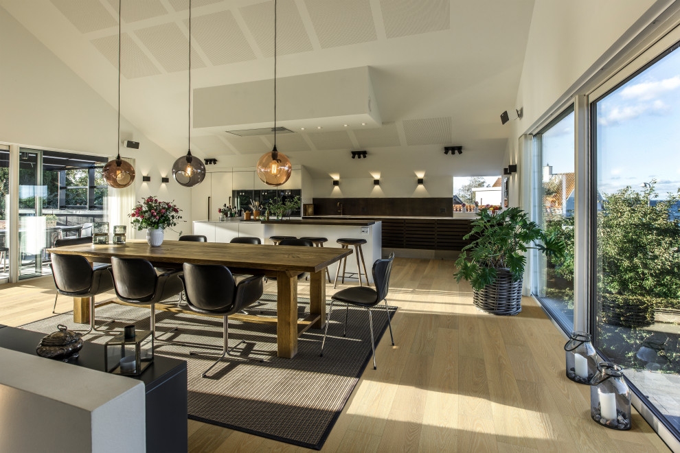 Photo of a large modern single-wall eat-in kitchen in Other with an integrated sink, louvered cabinets, dark wood cabinets, marble benchtops, brown splashback, timber splashback, panelled appliances, light hardwood floors, with island, multi-coloured floor, white benchtop and vaulted.