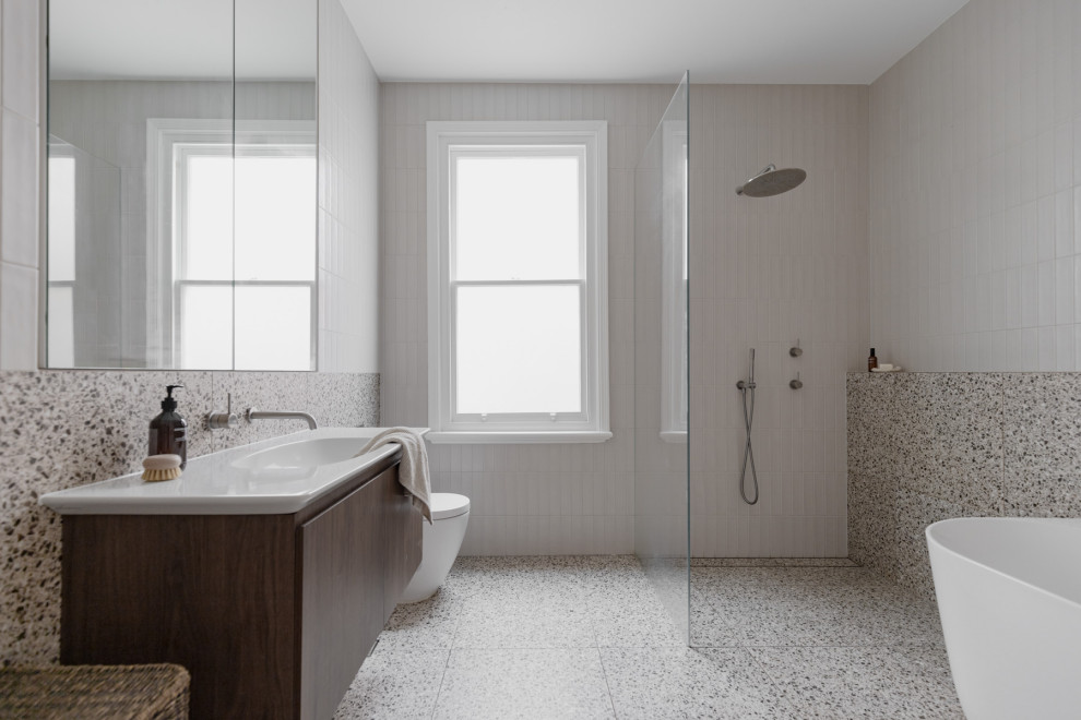 Inspiration for a large transitional master bathroom in Sydney with flat-panel cabinets, dark wood cabinets, a freestanding tub, an open shower, a one-piece toilet, white tile, ceramic tile, white walls, terrazzo floors, an integrated sink, grey floor, white benchtops, a single vanity and a floating vanity.