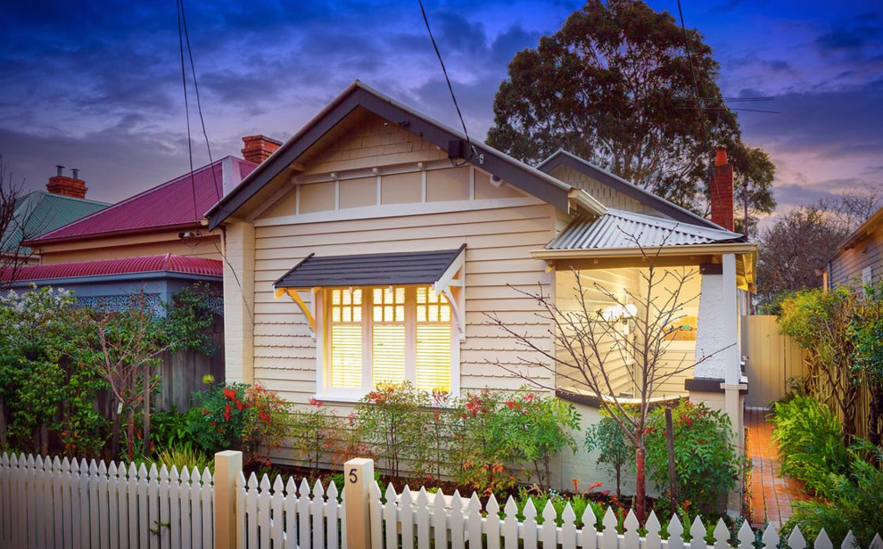 Photo of a mid-sized traditional one-storey beige house exterior in Melbourne with wood siding, a gable roof and a metal roof.