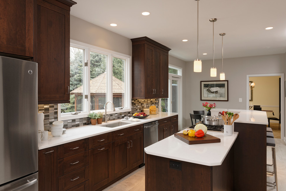 Mid-sized transitional l-shaped ceramic tile enclosed kitchen photo in Baltimore with a single-bowl sink, flat-panel cabinets, dark wood cabinets, quartz countertops, metallic backsplash, mosaic tile backsplash, stainless steel appliances and an island