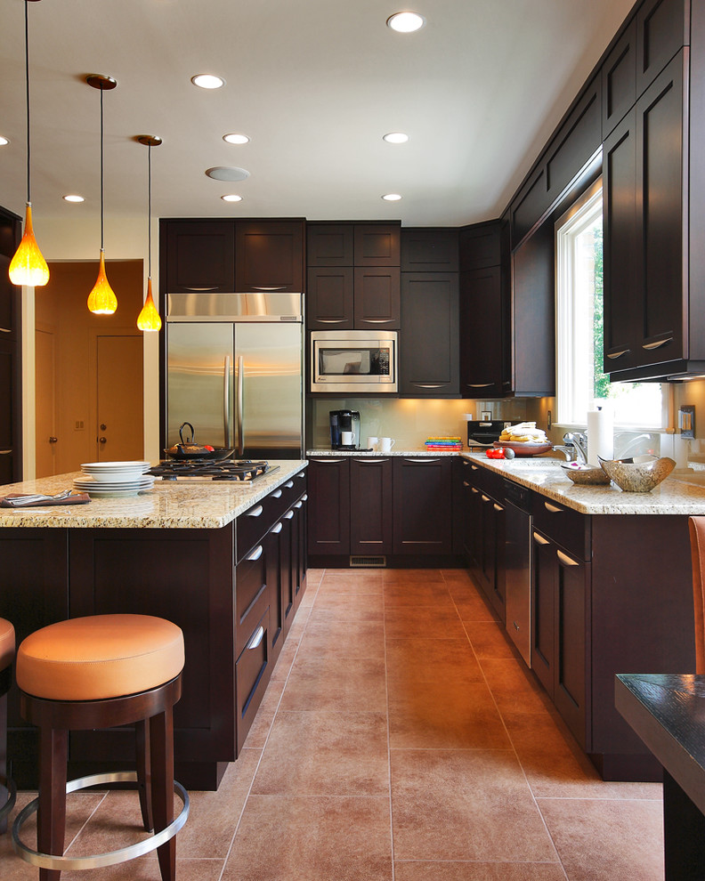 Photo of a large transitional u-shaped eat-in kitchen in DC Metro with an undermount sink, shaker cabinets, dark wood cabinets, granite benchtops, yellow splashback, glass sheet splashback, stainless steel appliances, ceramic floors and with island.