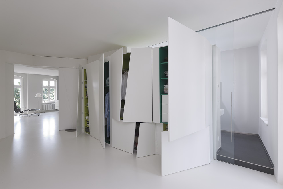This is an example of a large contemporary gender-neutral dressing room in Frankfurt with flat-panel cabinets, white cabinets and linoleum floors.