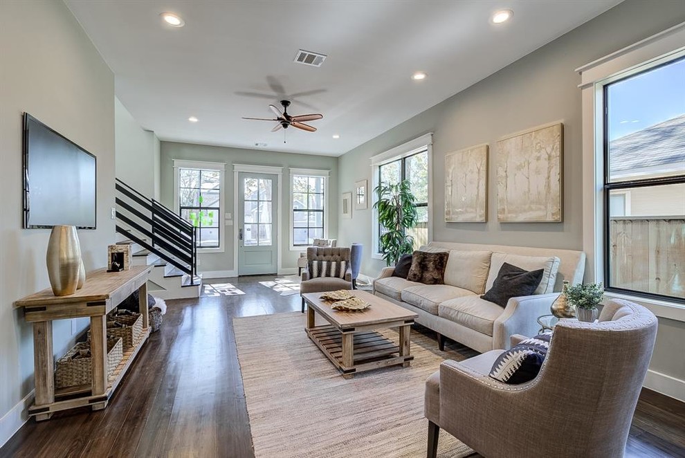 Inspiration for a mid-sized arts and crafts open concept living room in Houston with grey walls, dark hardwood floors, no fireplace, a wall-mounted tv and brown floor.