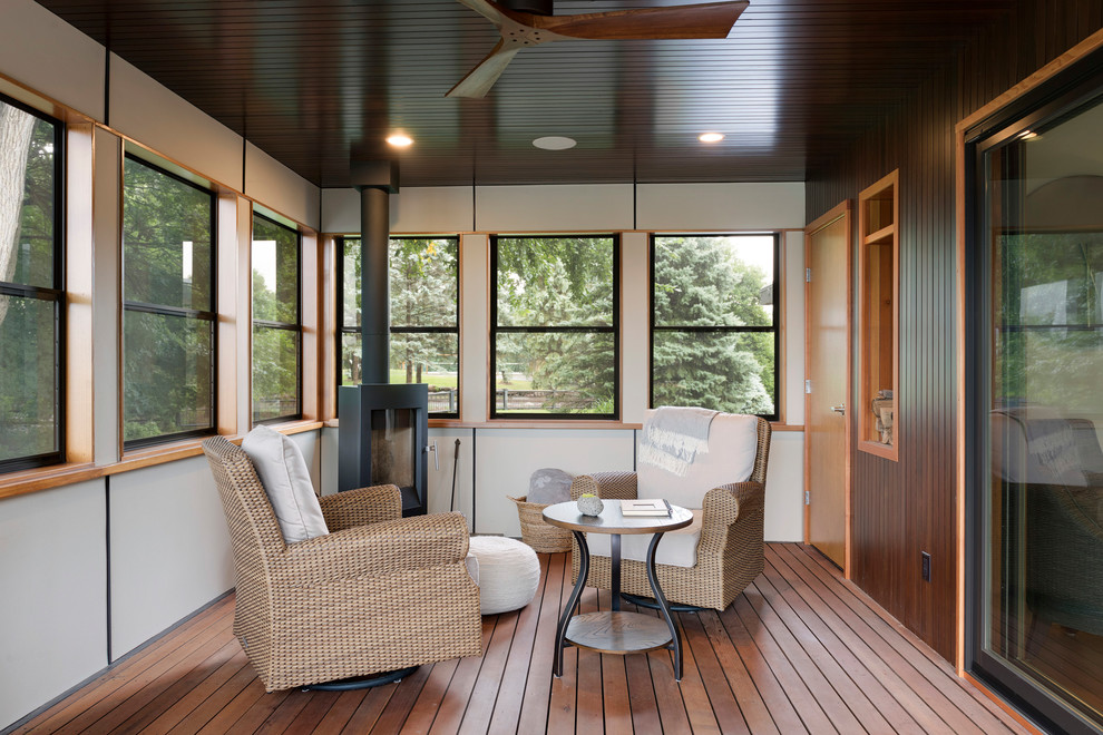 Photo of a midcentury sunroom in Minneapolis with medium hardwood floors, a wood stove and a standard ceiling.